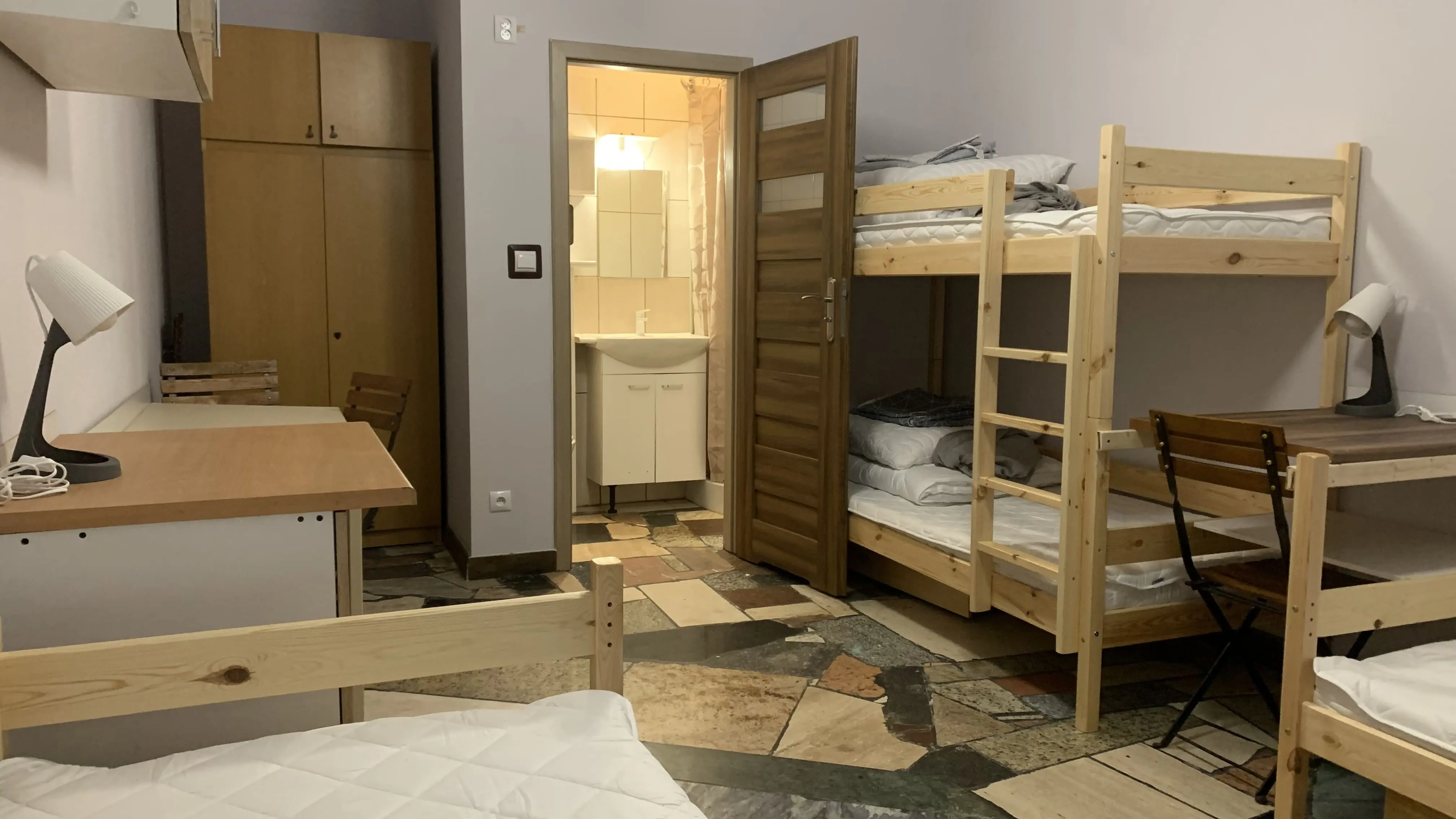 Jasna kwatera z dużą szafą, stolikiem i nowoczesnym wystrojem. Bliskość parkingu ułatwia pobyt osobom zmotoryzowanym.